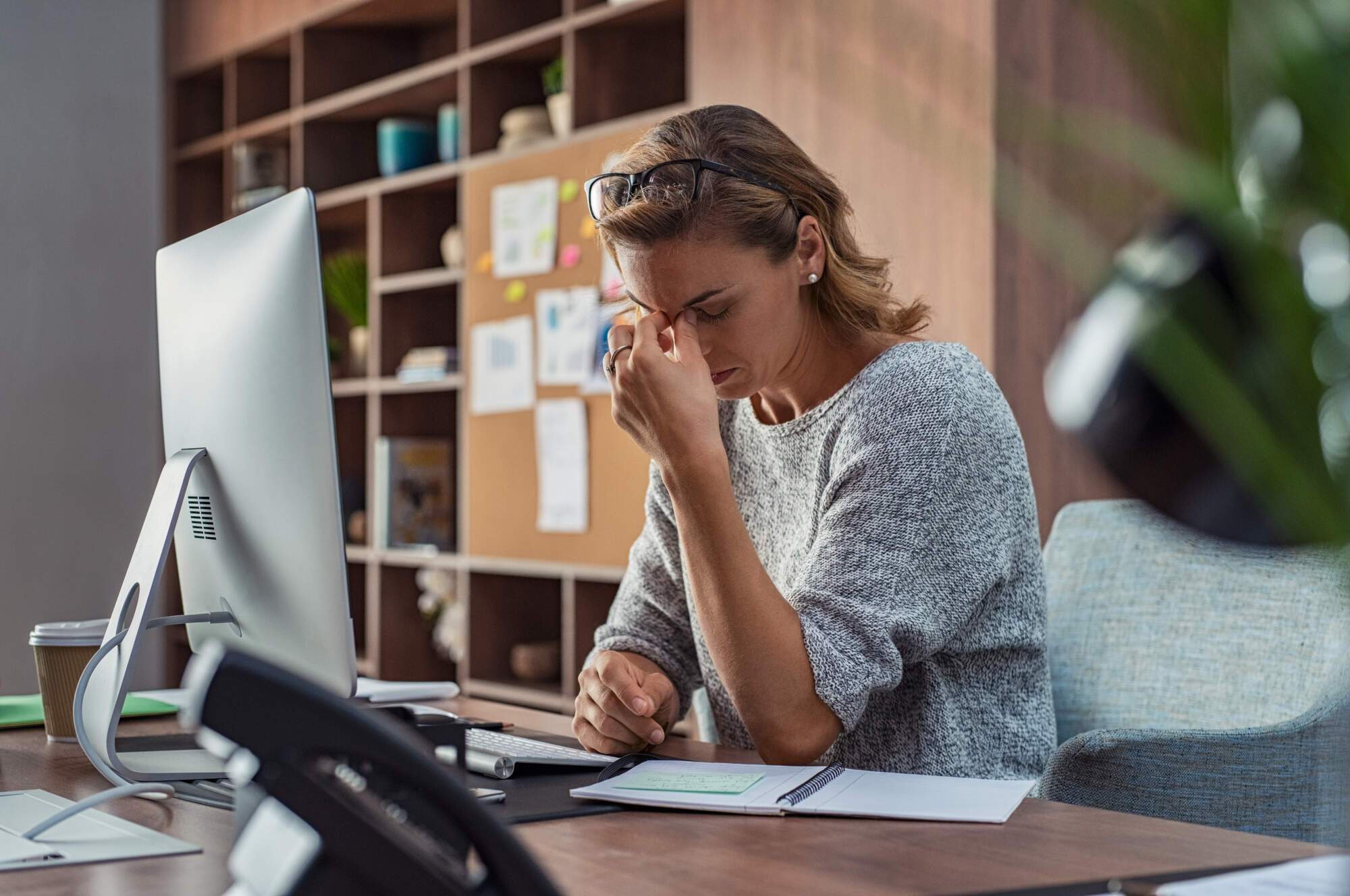 Woman With Headache At Desk Tension Headaches vs. Migraines